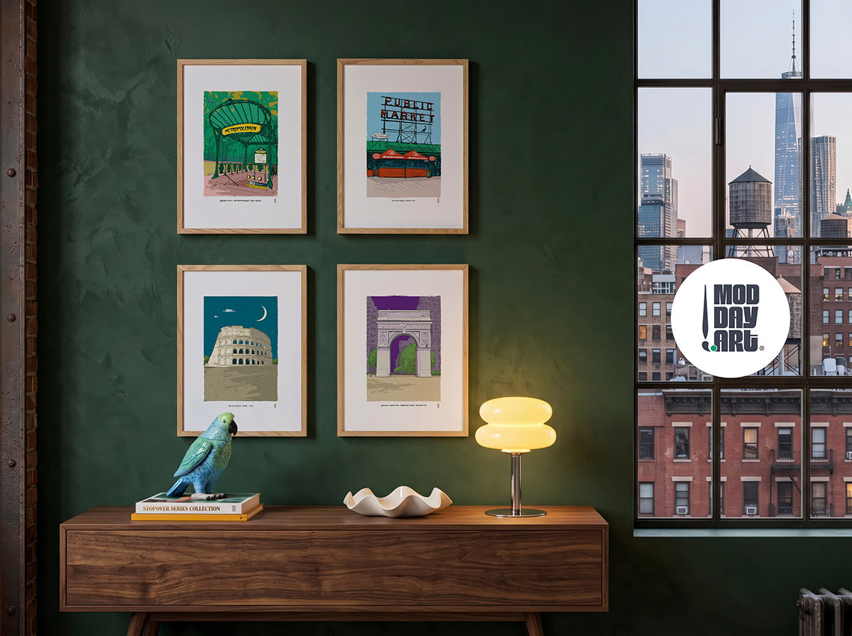 Four framed Stopover city art prints, Abbesses Station Paris, Pike Place Market Seattle, the Colosseum Rome, and Washington Square Park, displayed on a dark green wall above a console table with a city skyline view.