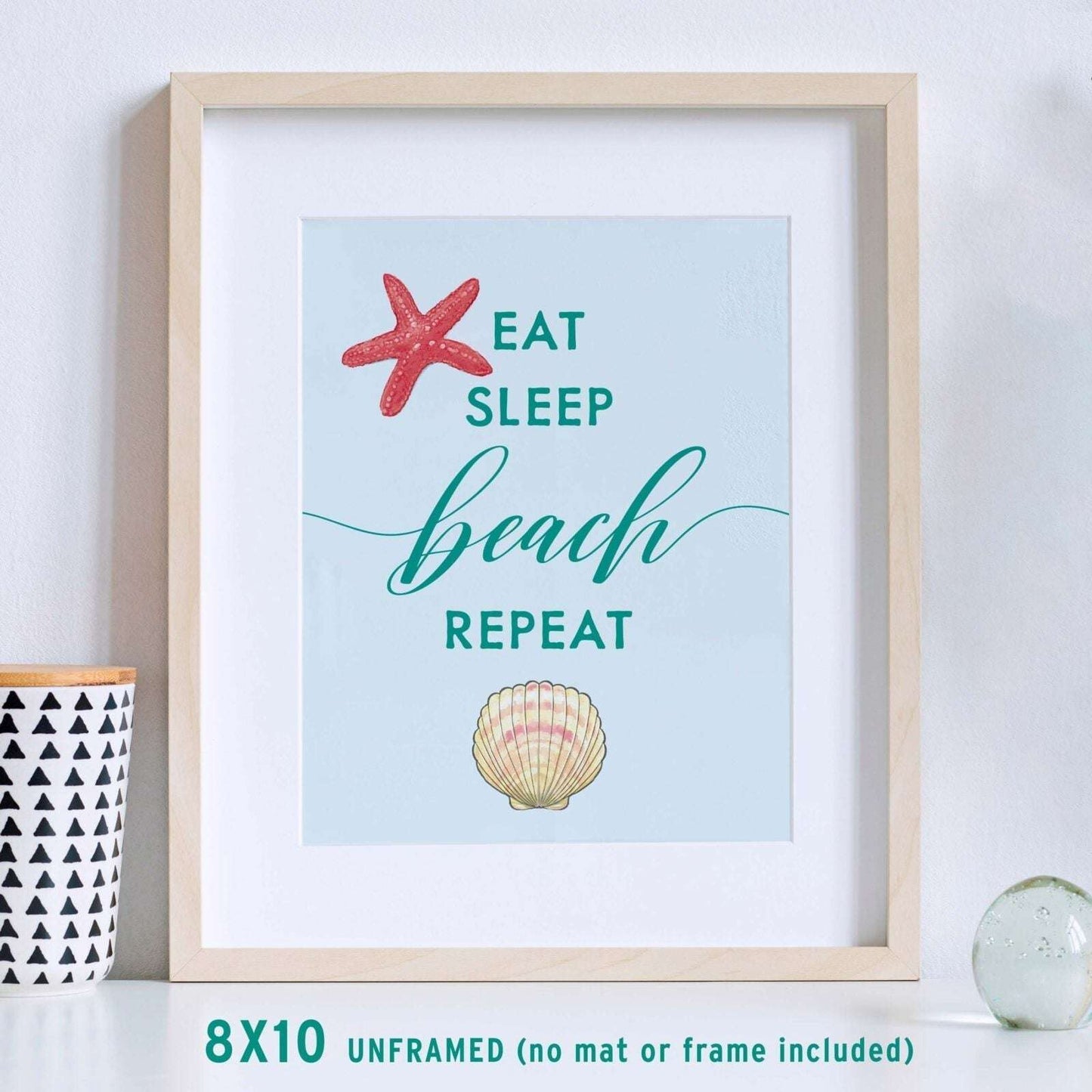 "Eat, Sleep, Beach, Repeat"  beach wall art shown in frame with hand-drawn starfish and scallop design.