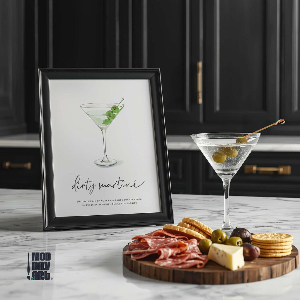 Framed Dirty Martini recipe cocktail wall art on a kitchen counter with a cocktail and charcuterie board.