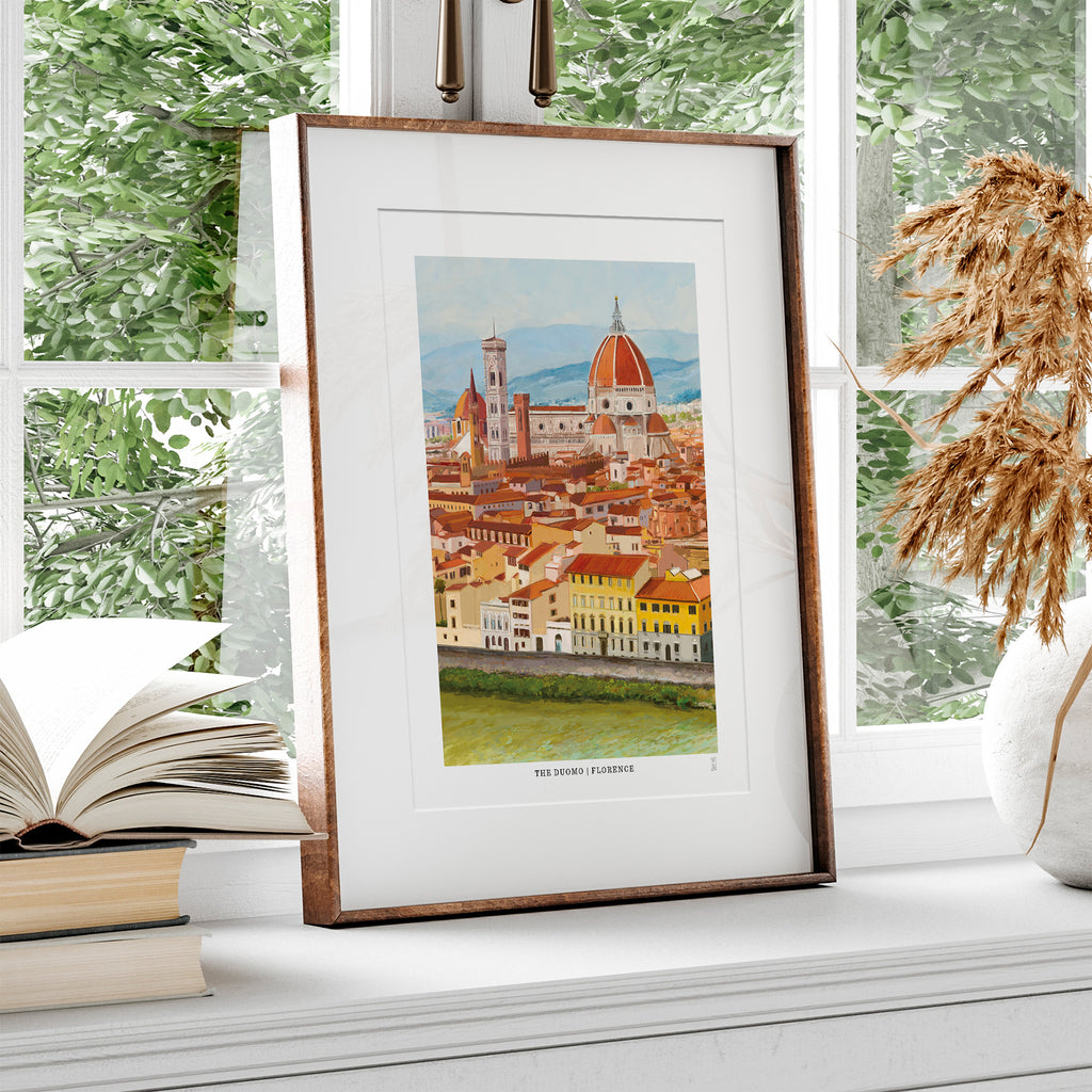 Framed hand-signed art print of The Duomo in Florence, Italy on a windowsill with books and decor.