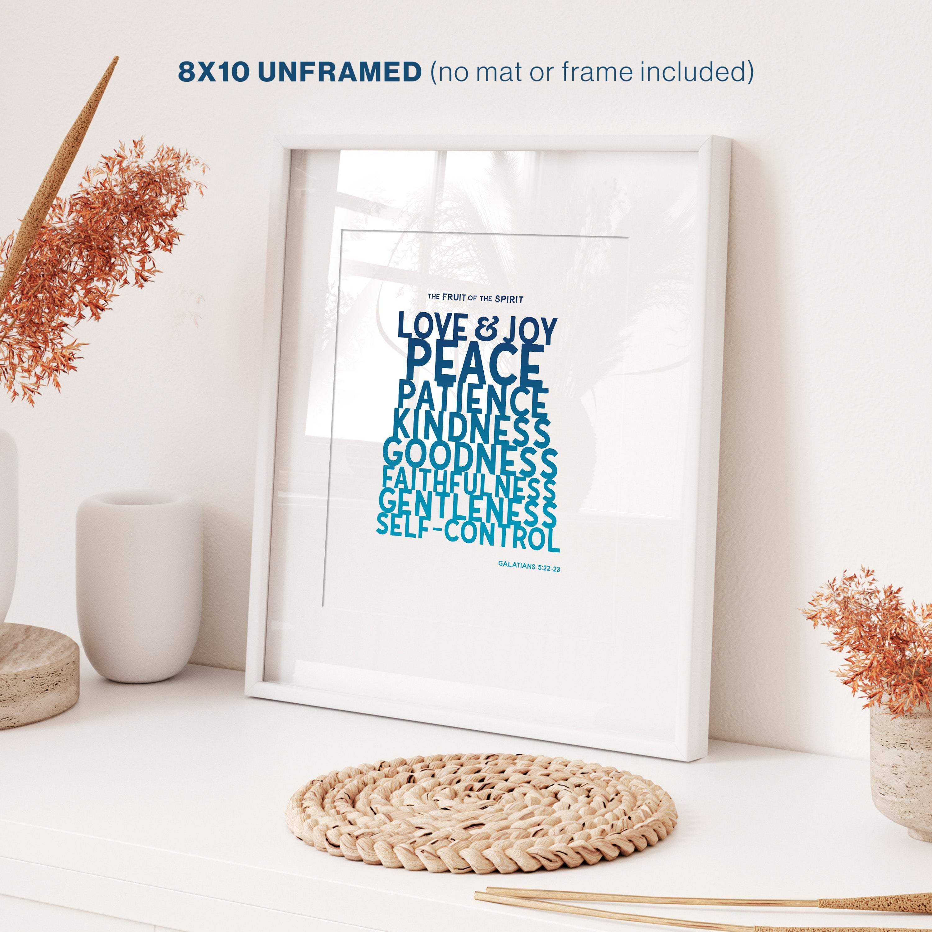 Fruit of the Spirit wall art print with motivational quote on a white surface with decorative items.