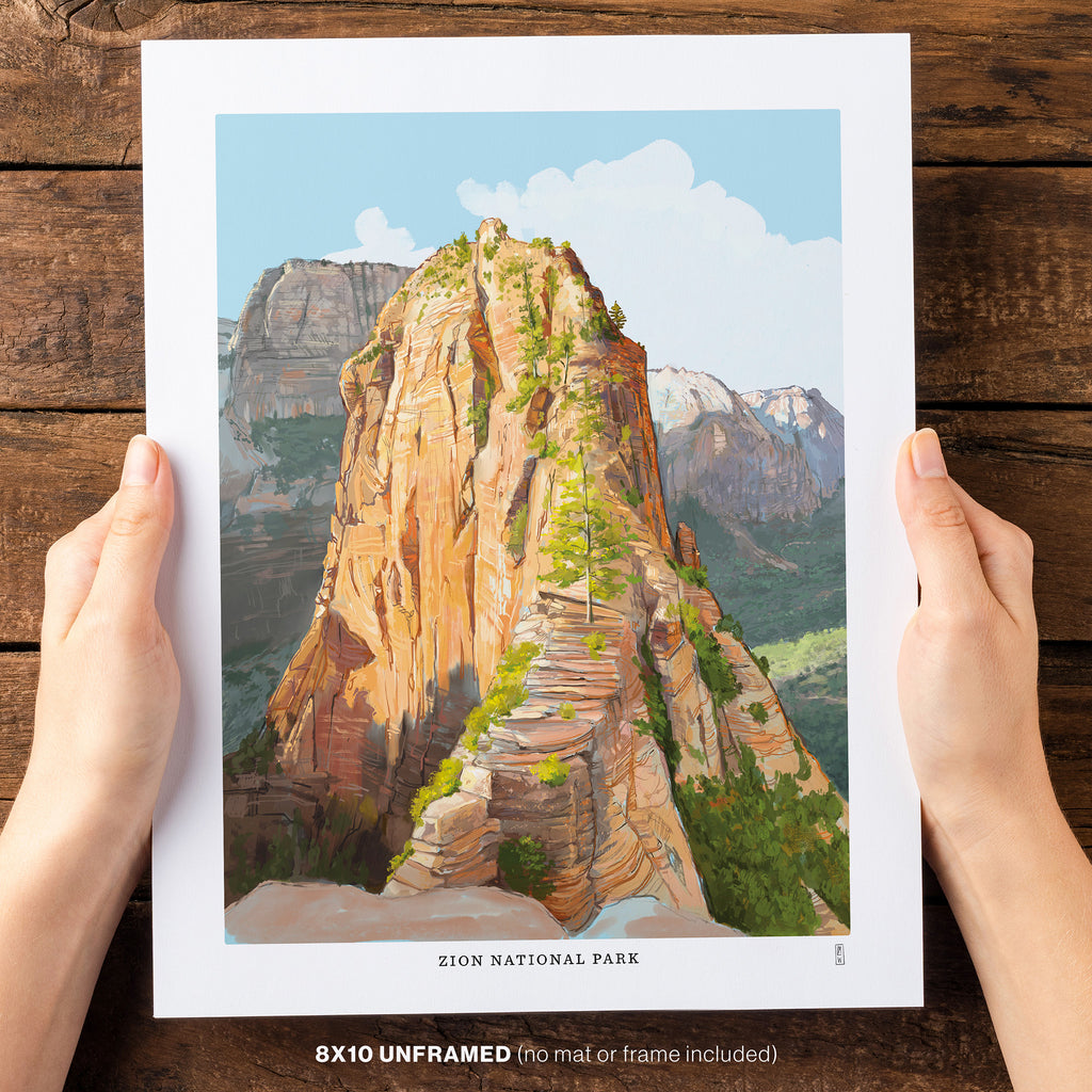Art print of Zion National Park held by hands on a wooden surface