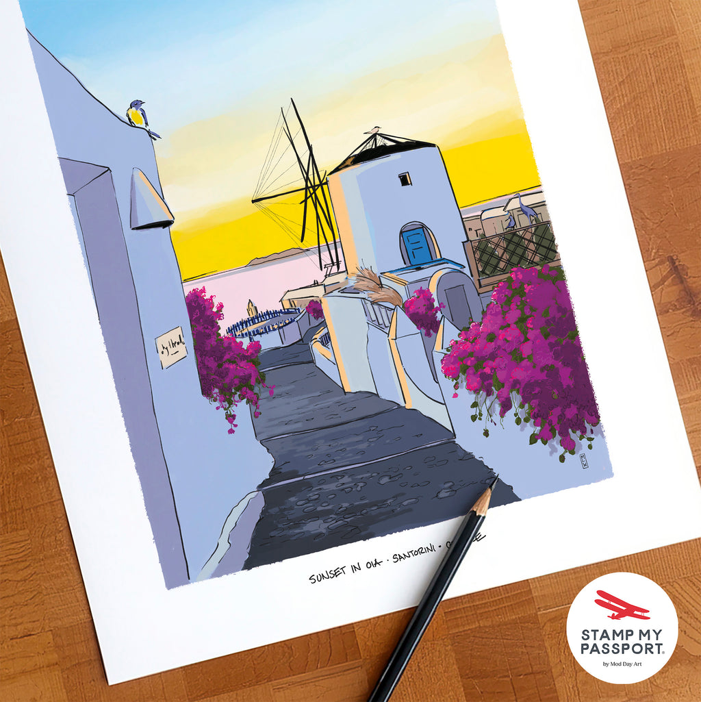 A colorful art print of a Santorini sunset scene with white buildings, a windmill, and magenta bougainvillea flowers, displayed on a wooden surface with a pencil and a Stamp My Passport logo sticker.