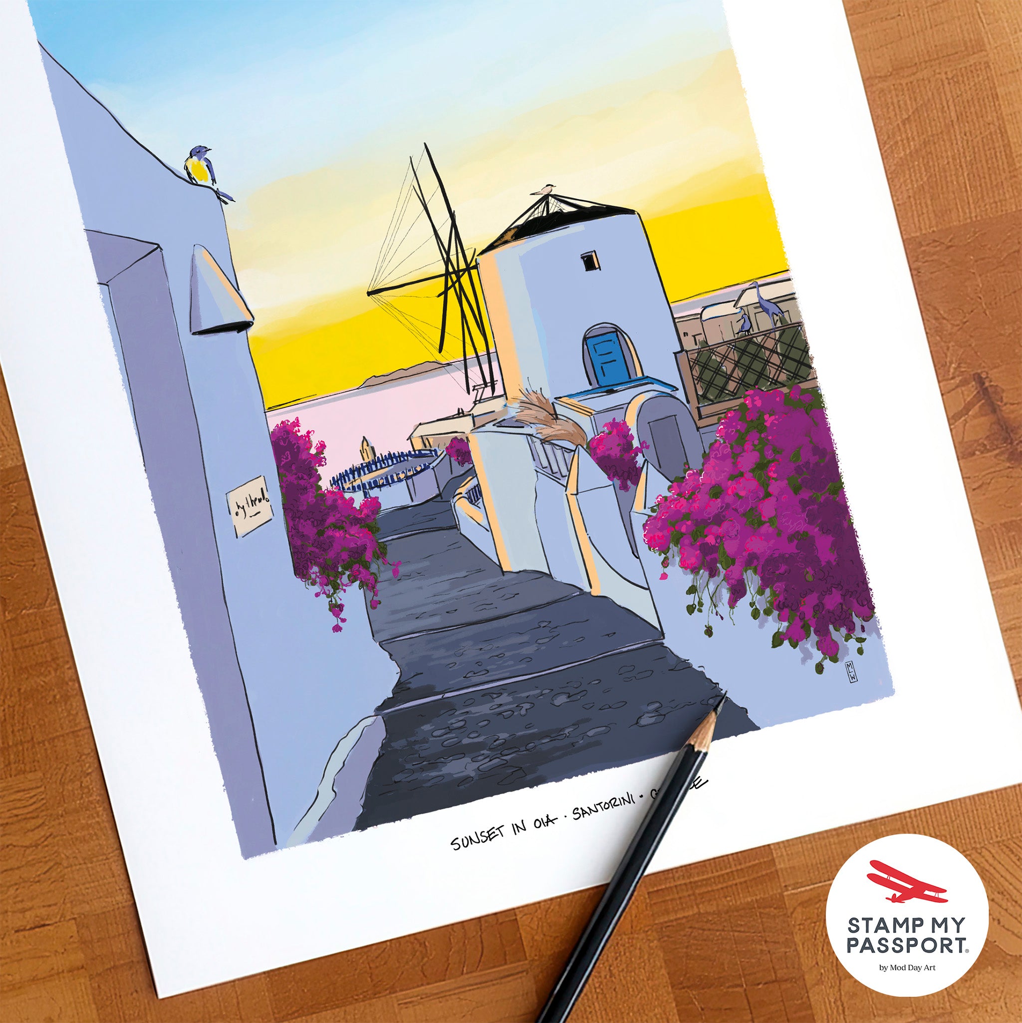 A colorful art print of a Santorini sunset scene with white buildings, a windmill, and magenta bougainvillea flowers, displayed on a wooden surface with a pencil and a Stamp My Passport logo sticker.