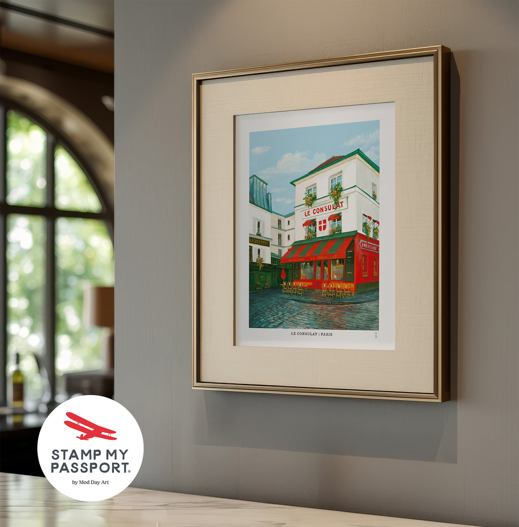 Framed artwork of Le Consulat cafe in Paris on a wall, featuring 'Stamp My Passport' logo.