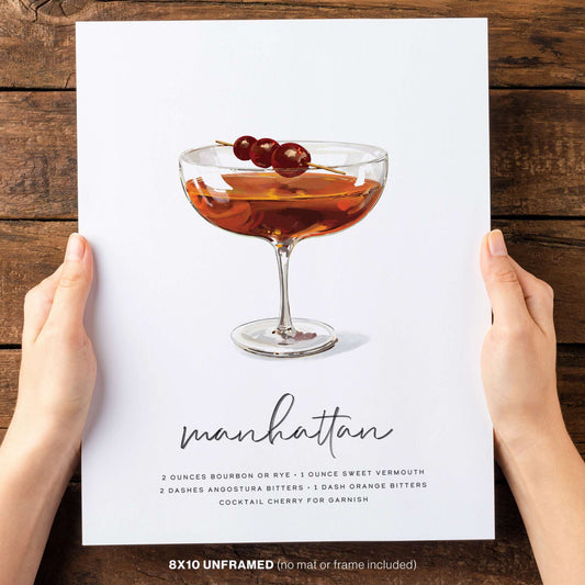 Two hands holding hand-drawn Manhattan Cocktail Wall Art.