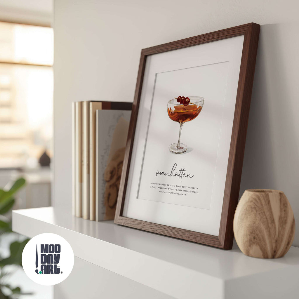 Framed print of a Manhattan recipe cocktail poster on a shelf with books and a vase.