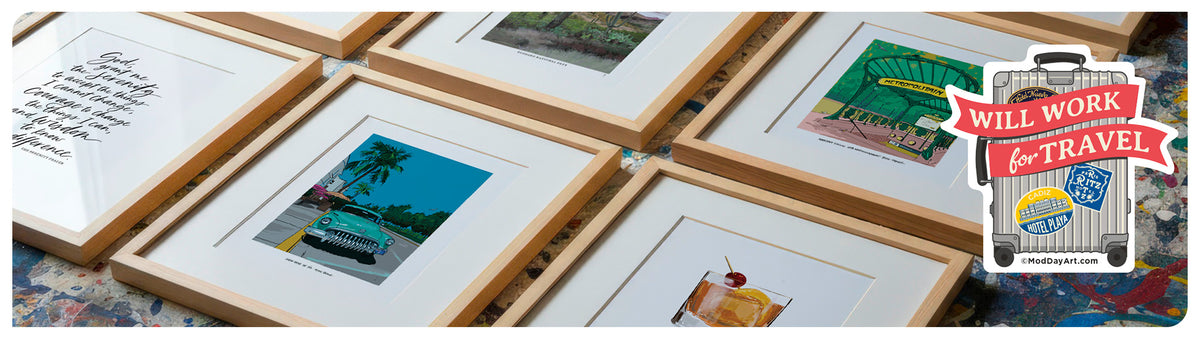 Six framed mod day art travel and cocktail prints with light wood frames and white mats are arranged on a colorful patterned surface.