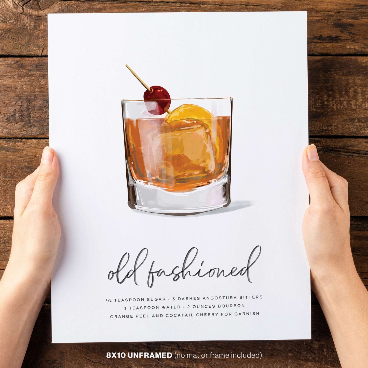 Two hands holding an 8x10 Old Fashioned recipe wall art, showcasing its stylish design and compact size.