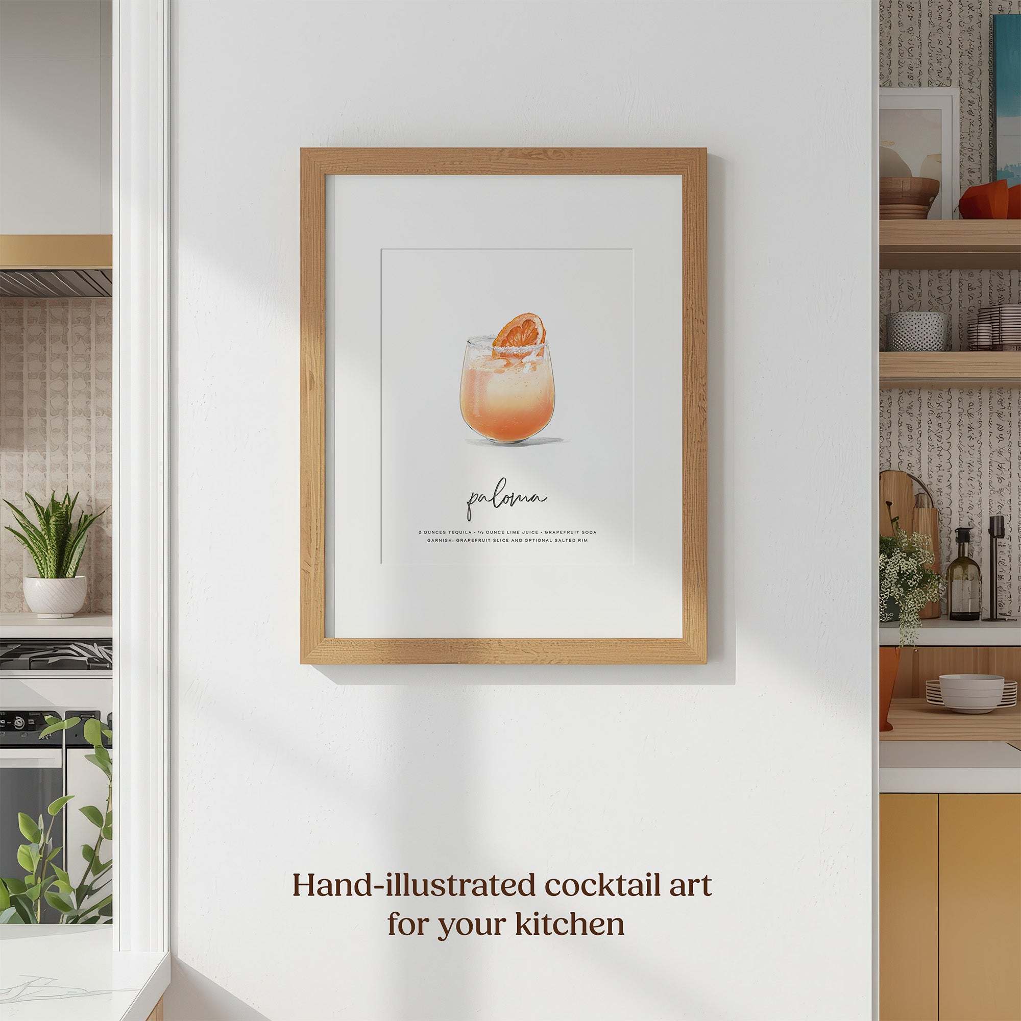 Framed Paloma recipe wall art in natural wood frame displayed on white kitchen wall, showing orange-pink cocktail illustration with grapefruit garnish.