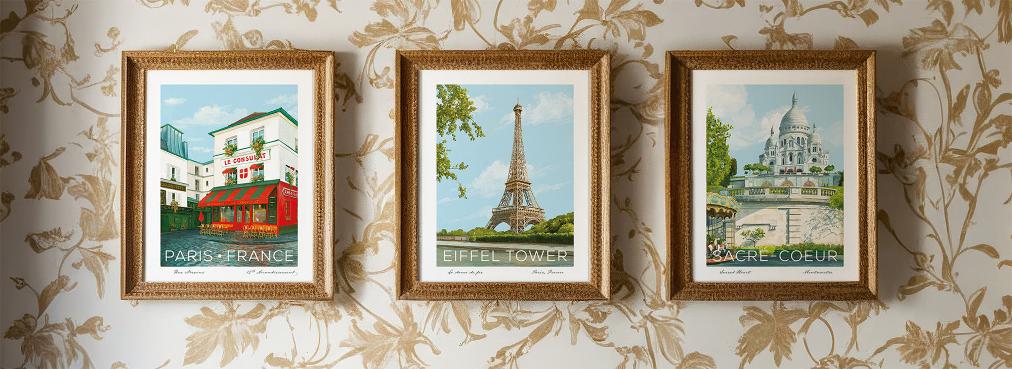 Three framed vintage Paris travel posters displayed on floral wallpaper, featuring Moulin Rouge street scene, Eiffel Tower, and Sacré-Cœur basilica in ornate gold frames.