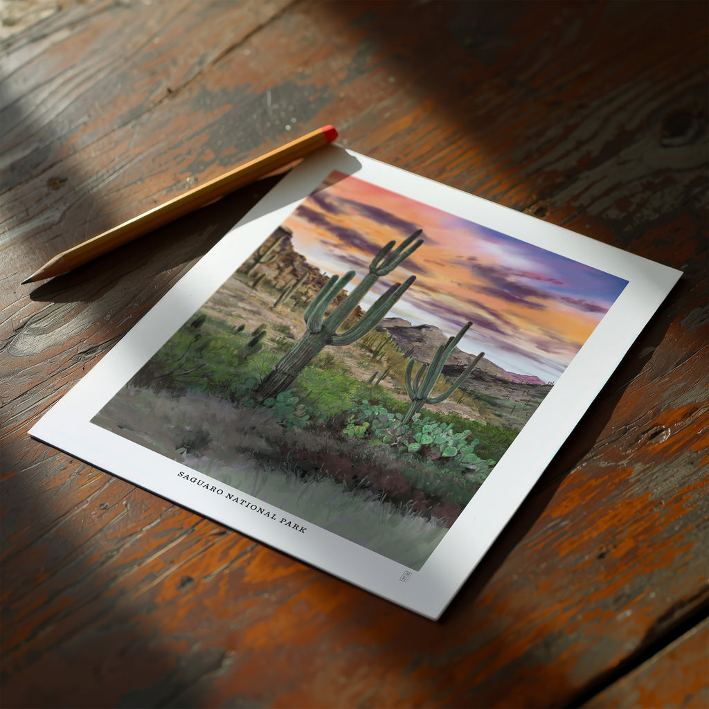 Hand-signed Saguaro National Park poster with cacti on a wooden table.
