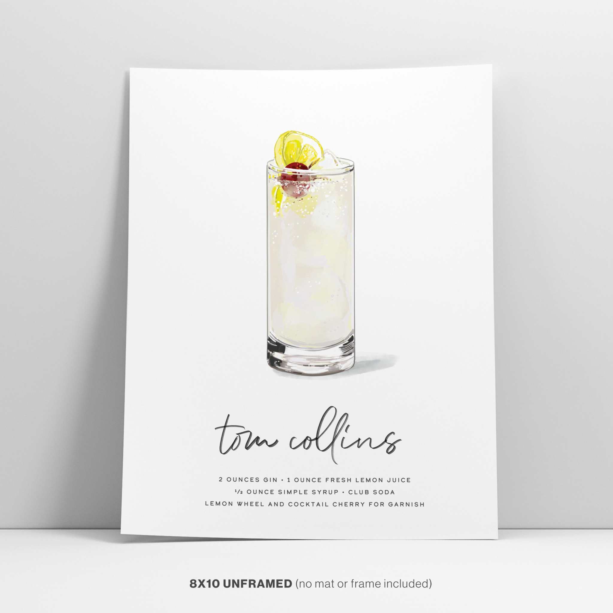 Tom Collins cocktail wall art leaning against a light grey wall.