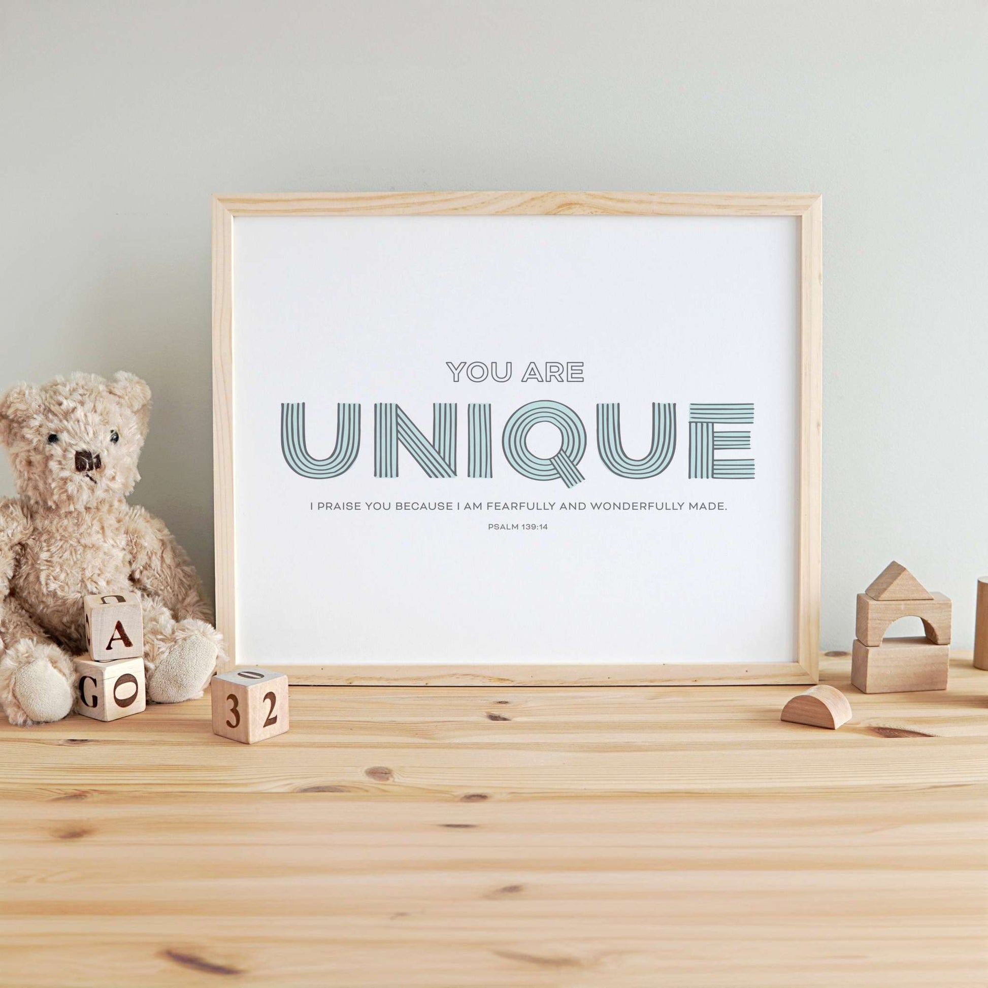The Scriptionery™ “Unique” nursery art print showcased in a modern wood frame, complemented by nursery decor accessories for a comfy feel.