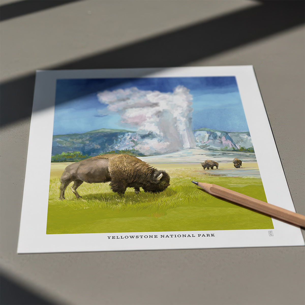 Hand-signed print of Yellowstone National Park with a bison and geysers on a gray surface.