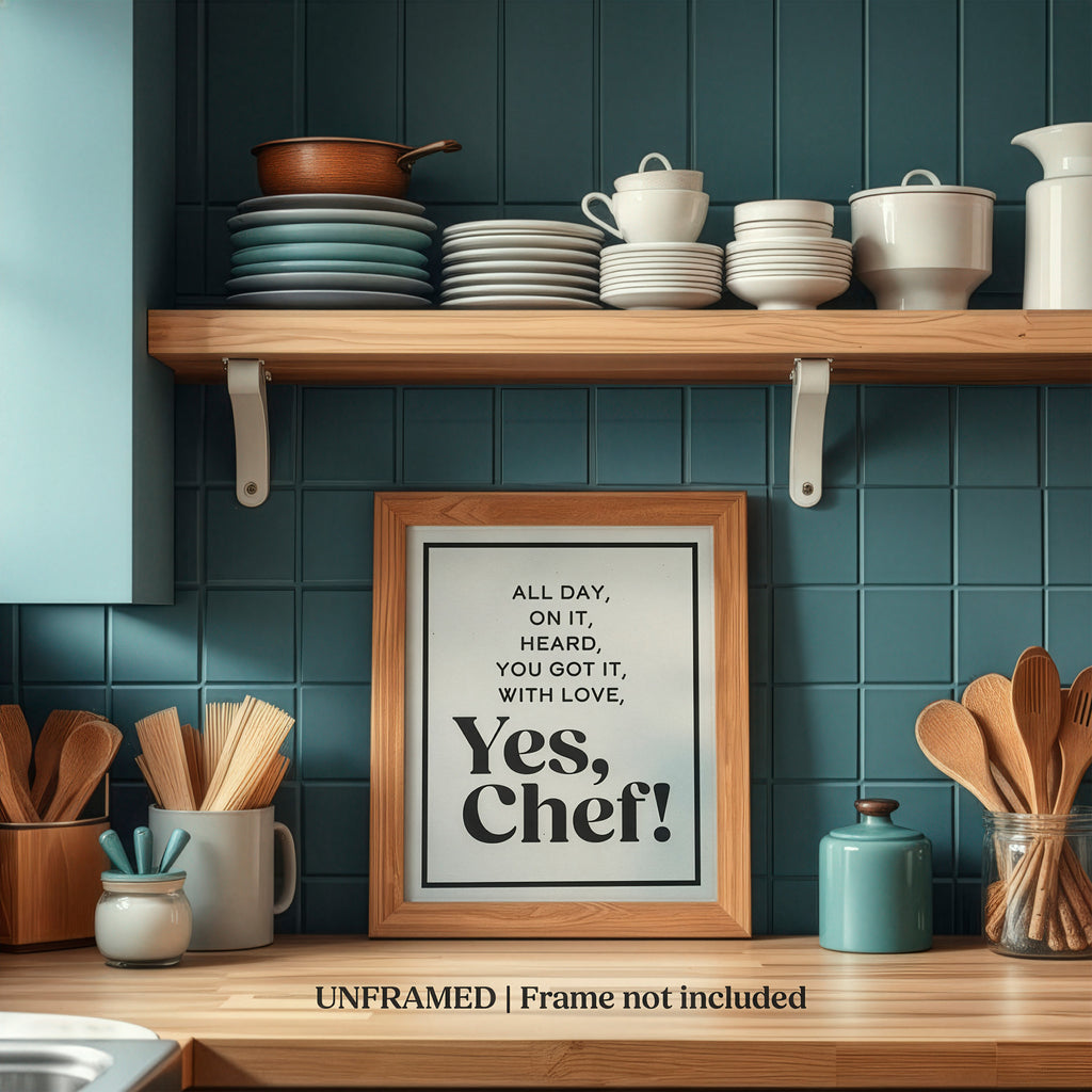 Kitchen shelf with utensils and a framed Mod Day Art Yes Chef kitchen wall art quote on a teal tiled wall.